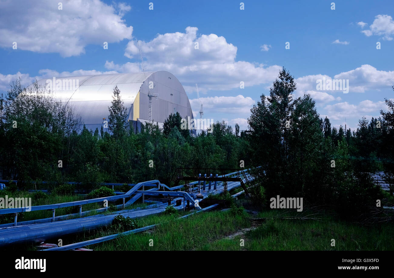 Vue sur les tubes en acier, qui ont été portées au-dessus du sol depuis l'accident de Tchernobyl pour éviter de creuser dans le sol contaminé, à proximité de la nouvelle structure de confinement en acier nommé la nouvelle enceinte de confinement (NSC) construit pour remplacer le vieillissant et construites à la hâte sarcophage qui protège actuellement le réacteur n°4 et devrait être terminée d'ici la fin de 2016 à l'intérieur de la zone d'exclusion de Tchernobyl en Ukraine le 04 juin 2016. L'accident de Tchernobyl a eu lieu le 26 avril 1986 à la centrale nucléaire de Tchernobyl, dans la ville de Pripyat et était la pire nuclear power plant Banque D'Images