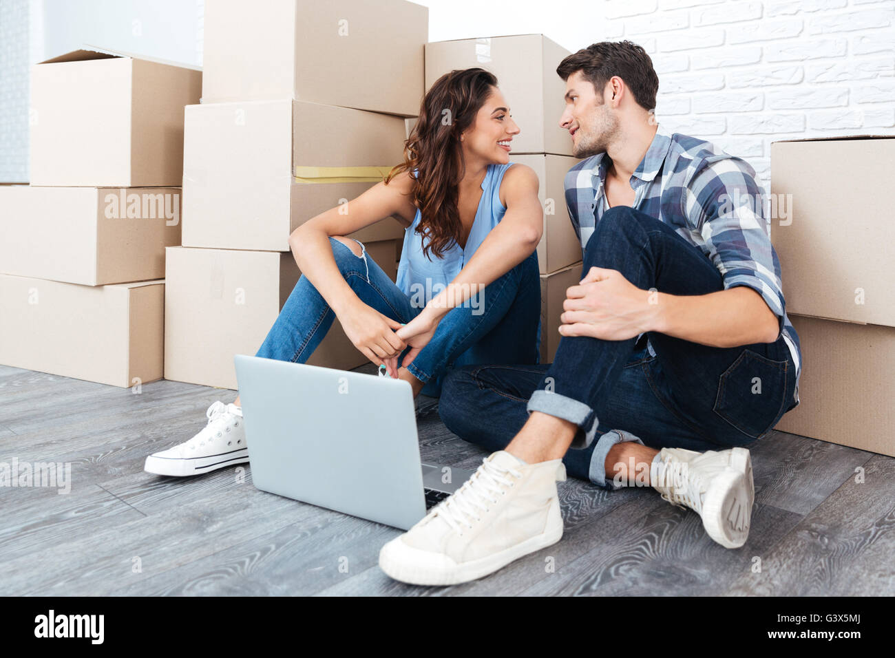 Jeune couple amoureux assis sur le plancher de leur nouvel appartement using laptop Banque D'Images