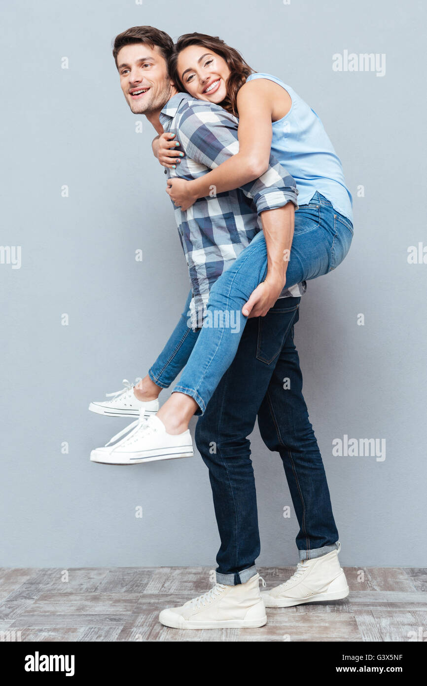 Jeune couple enjoying piggyback ride isolé sur fond gris Banque D'Images