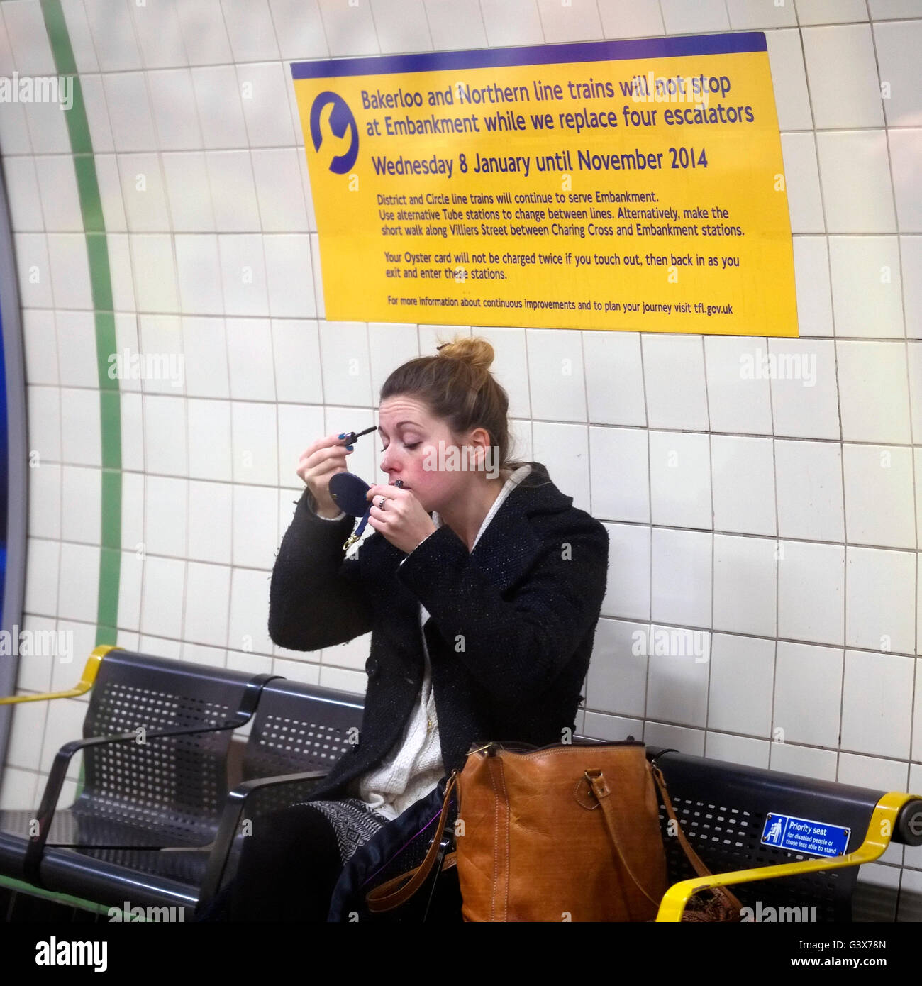 Faire commuter le maquillage sur la plate-forme d'une station de métro de Londres sur le chemin du travail. Banque D'Images