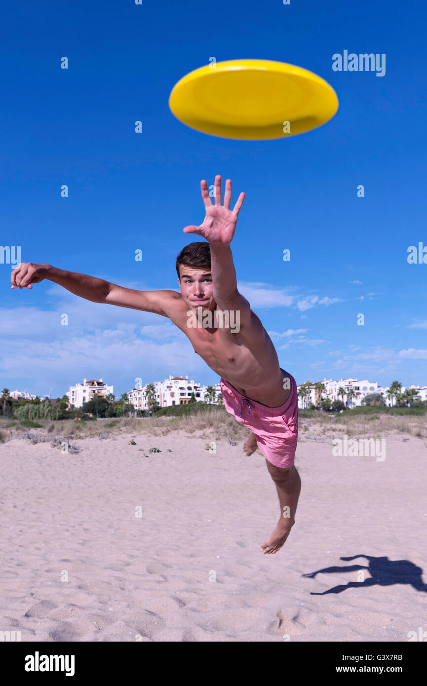 Garçon plonge pour attraper Frisbee. Boy est lancé pour capturer le frisbee sur la plage Banque D'Images