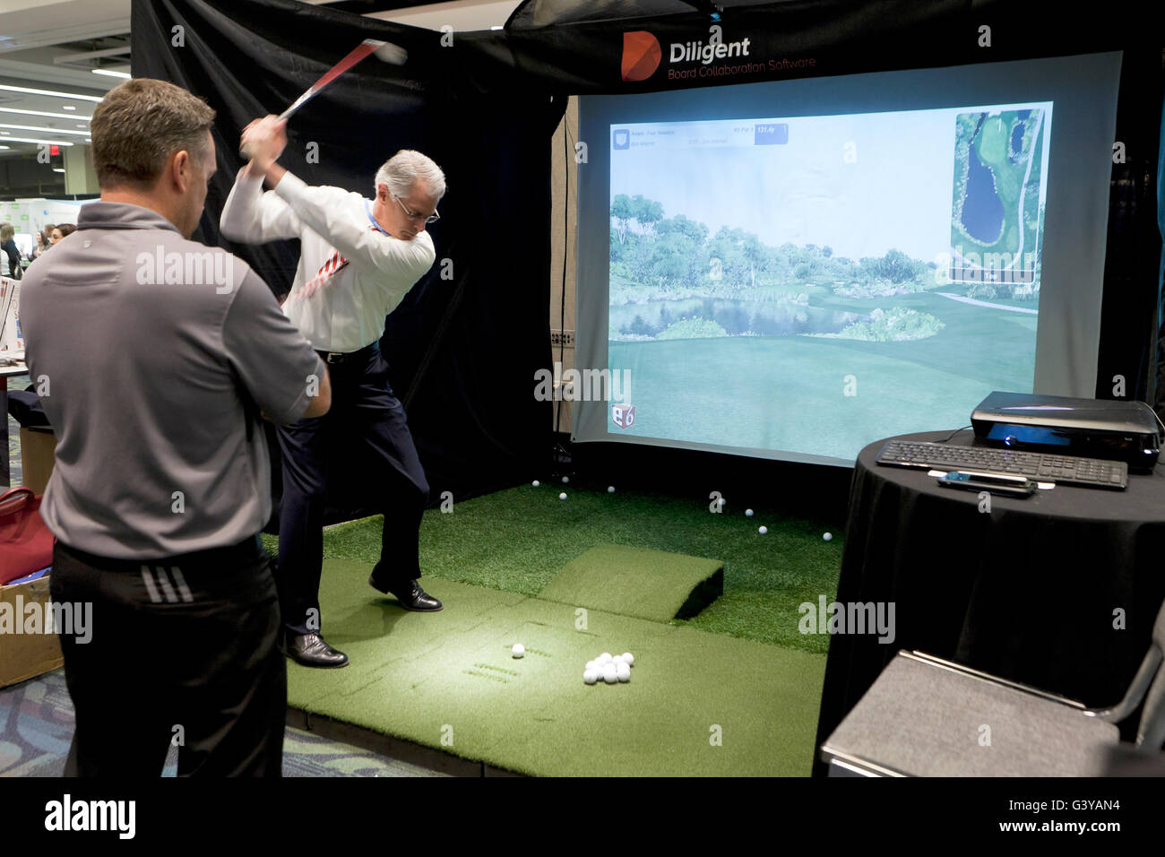 Businessman pris le départ à un simulateur de golf - USA Banque D'Images