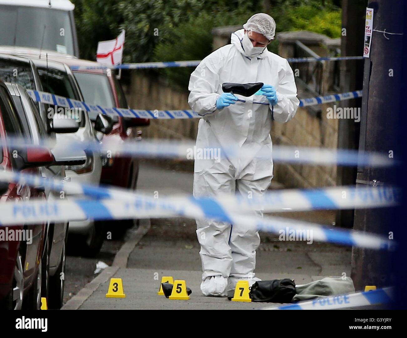 Un agent de police scientifique regarde une femme de service sur les lieux en Birstall, West Yorkshire, après la mort du travail MP Jo Cox, qui est mort après avoir été abattu et poignardé dans la rue à l'extérieur de sa circonscription conseils la chirurgie. Banque D'Images