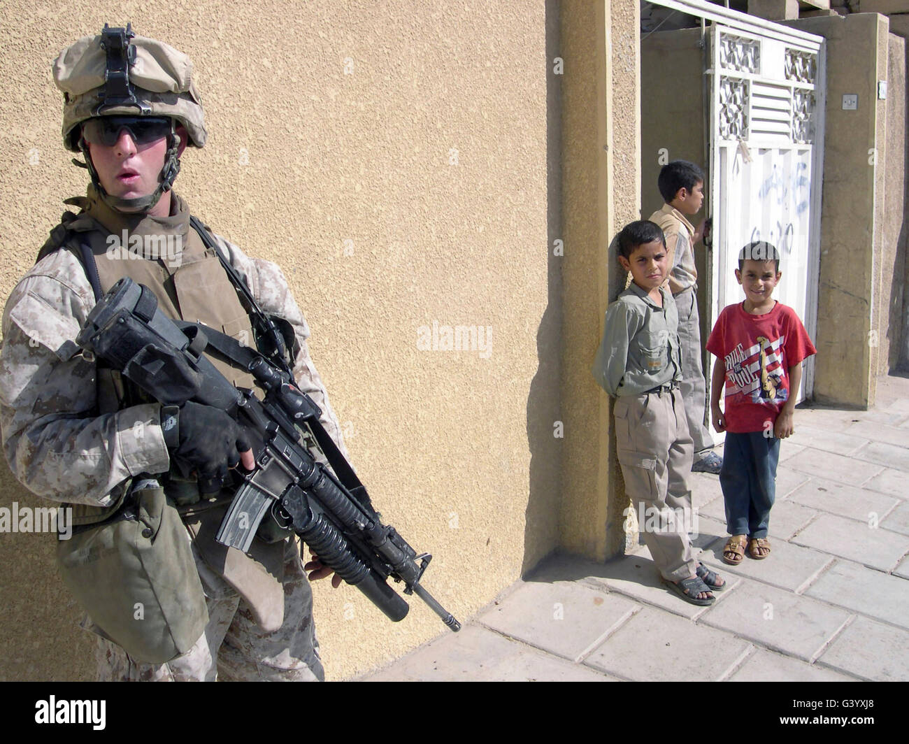 Un groupe d'enfants irakiens observer un Marine armé d'un 5,56 mm M16A2 carabine. Banque D'Images