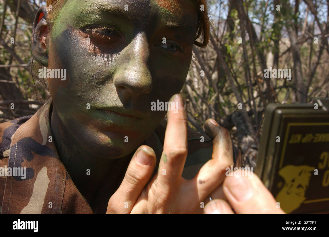 Airman applique la peinture de camouflage à son visage. Banque D'Images