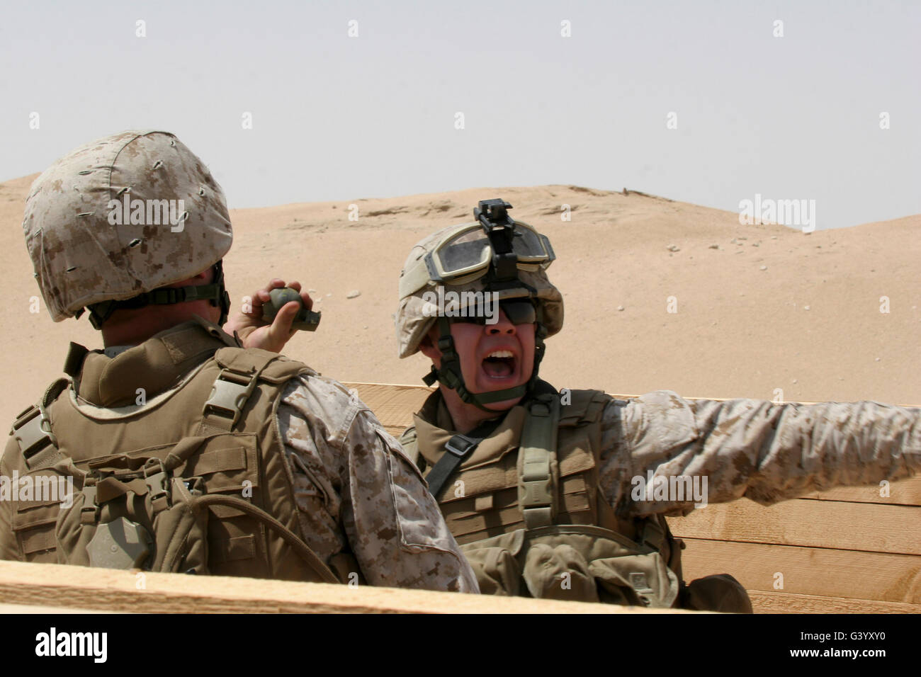 Un soldat regarde un fellow de lancer une grenade à main. Banque D'Images