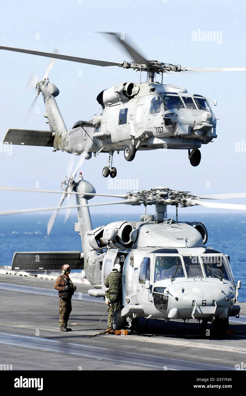 Hélicoptère Seahawk de l'US Navy d'un levé de USS Abraham Lincoln que l'équipage d'un autre se prépare pour le vol. Banque D'Images