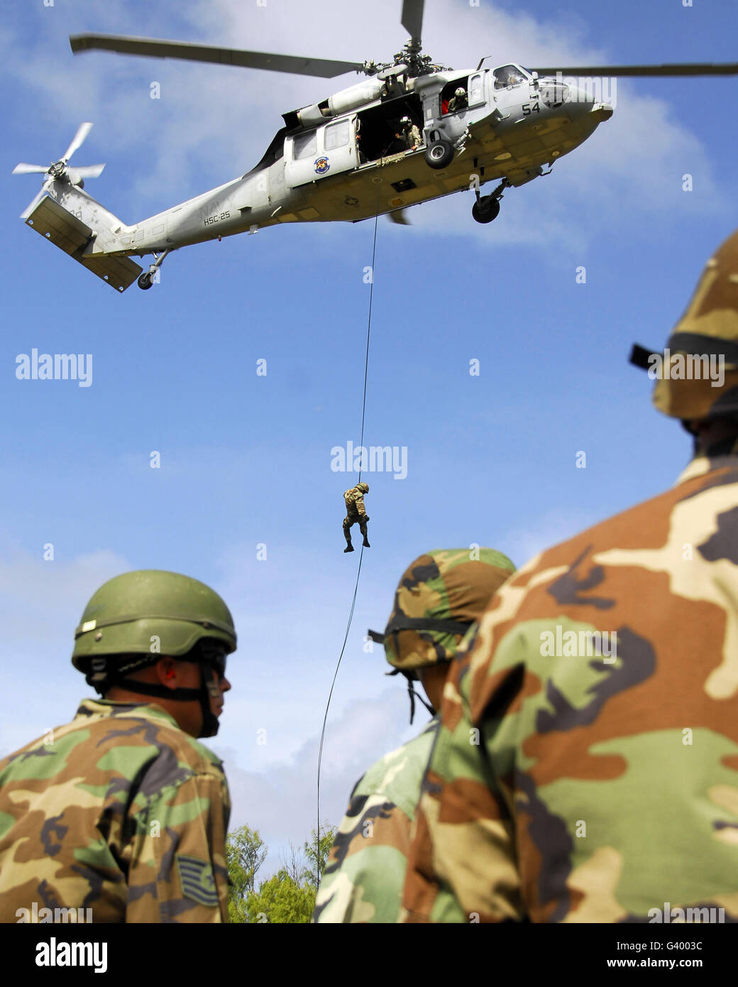 Les aviateurs de l'équipe d'assaut de l'air regarder comme un autre membre de l'équipe rappels d'un HH-60 Pave Hawk helicopter. Banque D'Images
