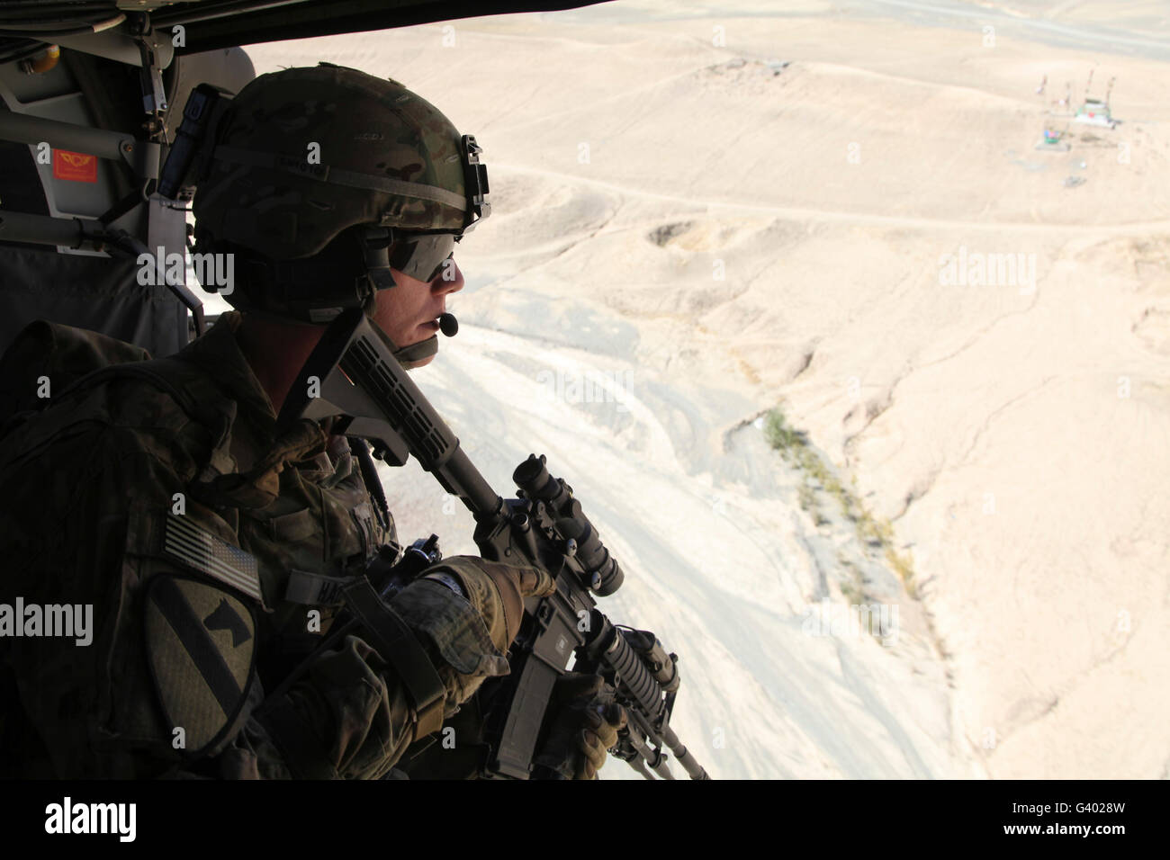 Le capitaine de l'armée américaine regarde par la porte d'un UH-60 Black Hawk sur l'Afghanistan. Banque D'Images
