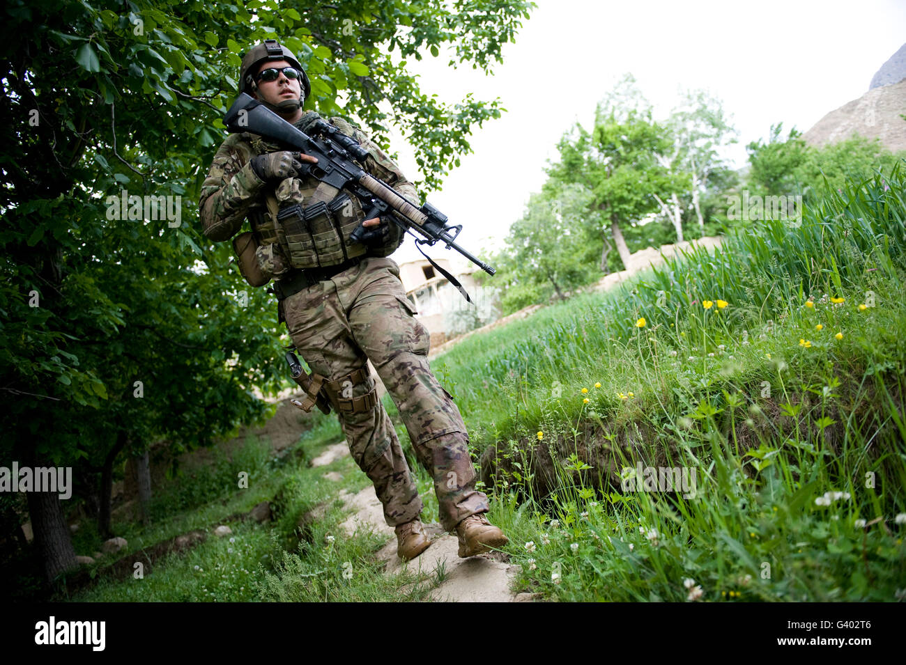 Spécialiste de l'armée américaine promenades à travers un champ en Afghanistan. Banque D'Images
