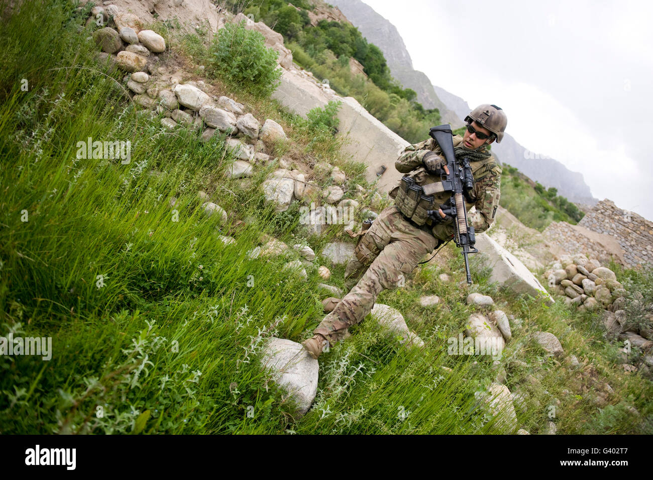 Spécialiste de l'armée américaine promenades à travers un champ en Afghanistan. Banque D'Images