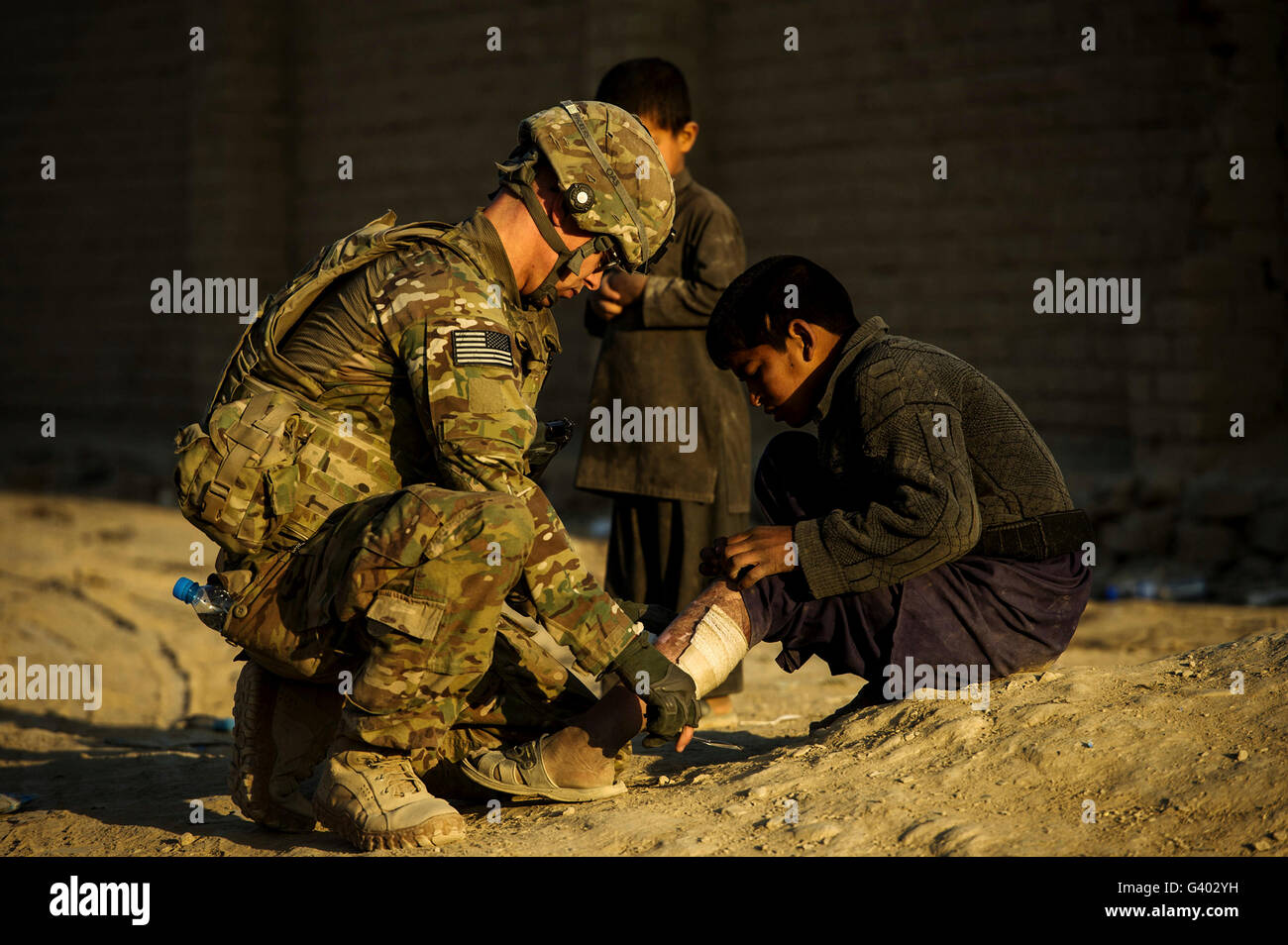 Airman fournit une aide médicale à un Afghan garçon. Banque D'Images