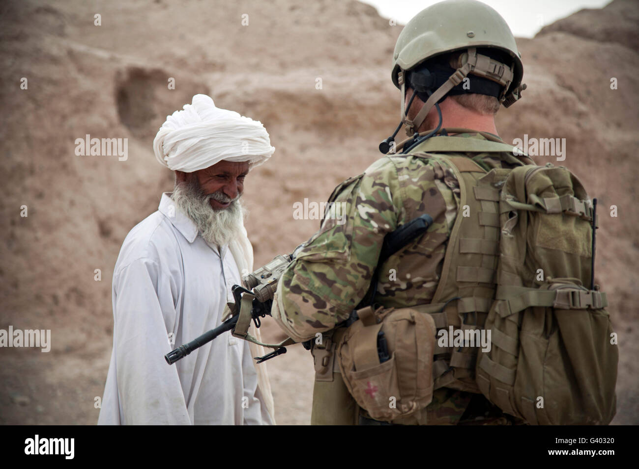 Un membre de la force de coalition parle avec un villageois afghans. Banque D'Images