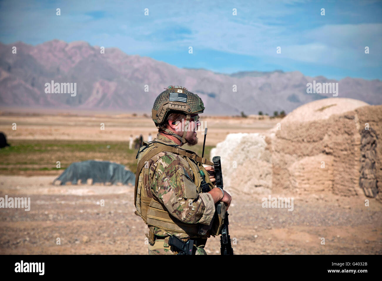 Un membre de la force de coalition assure la sécurité à la périphérie d'un village afghan. Banque D'Images