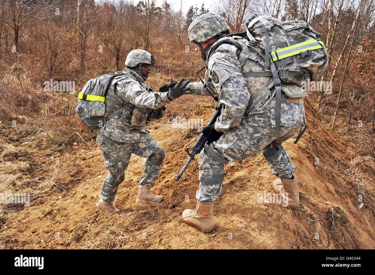 Les soldats de l'armée américaine aide un autre soldat traverser un terrain accidenté. Banque D'Images