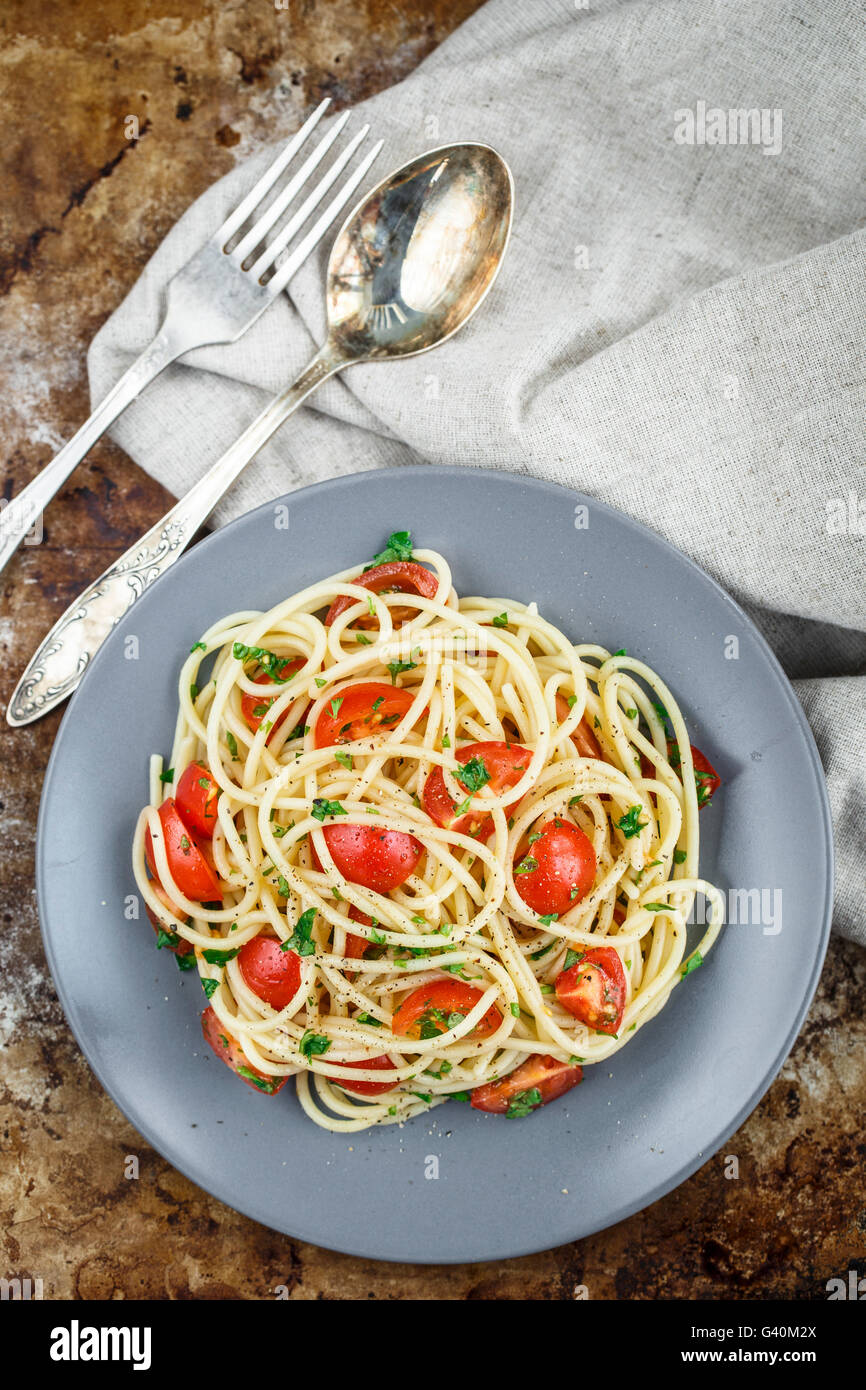 Les pâtes Spaghetti aux tomates cerises et le persil sur arrière-plan rustric Banque D'Images