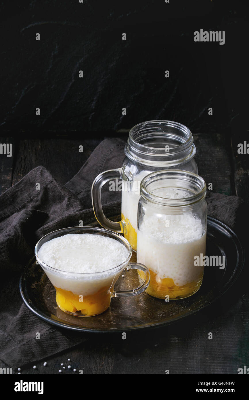 Des perles de tapioca au lait dessert avec du lait de coco et mangue. Servis dans des bocaux en verre sur plateau vintage iron plus ancienne en bois ta Banque D'Images