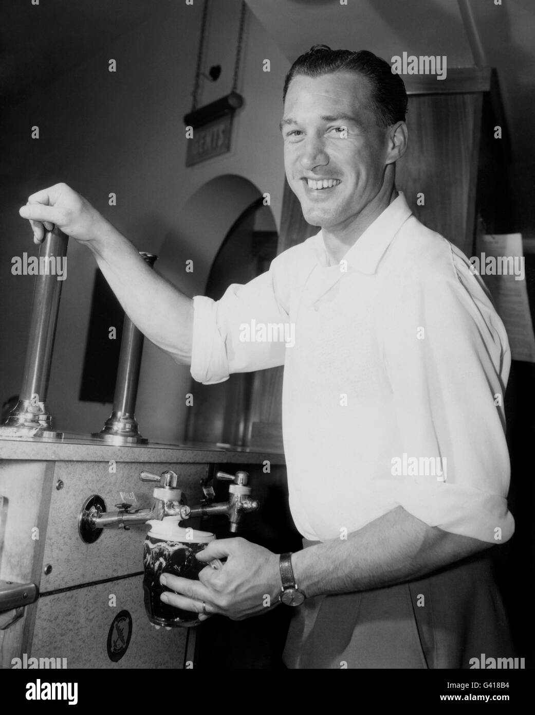 NAT Lofthouse, Bolton Wanderers et le centre d'Angleterre en avant, qui a pris le contrôle de l'hôtel Castle à Bolton, Lancashire. Il est vu dessiner une pinte de bière derrière le bar de l'hôtel. Banque D'Images