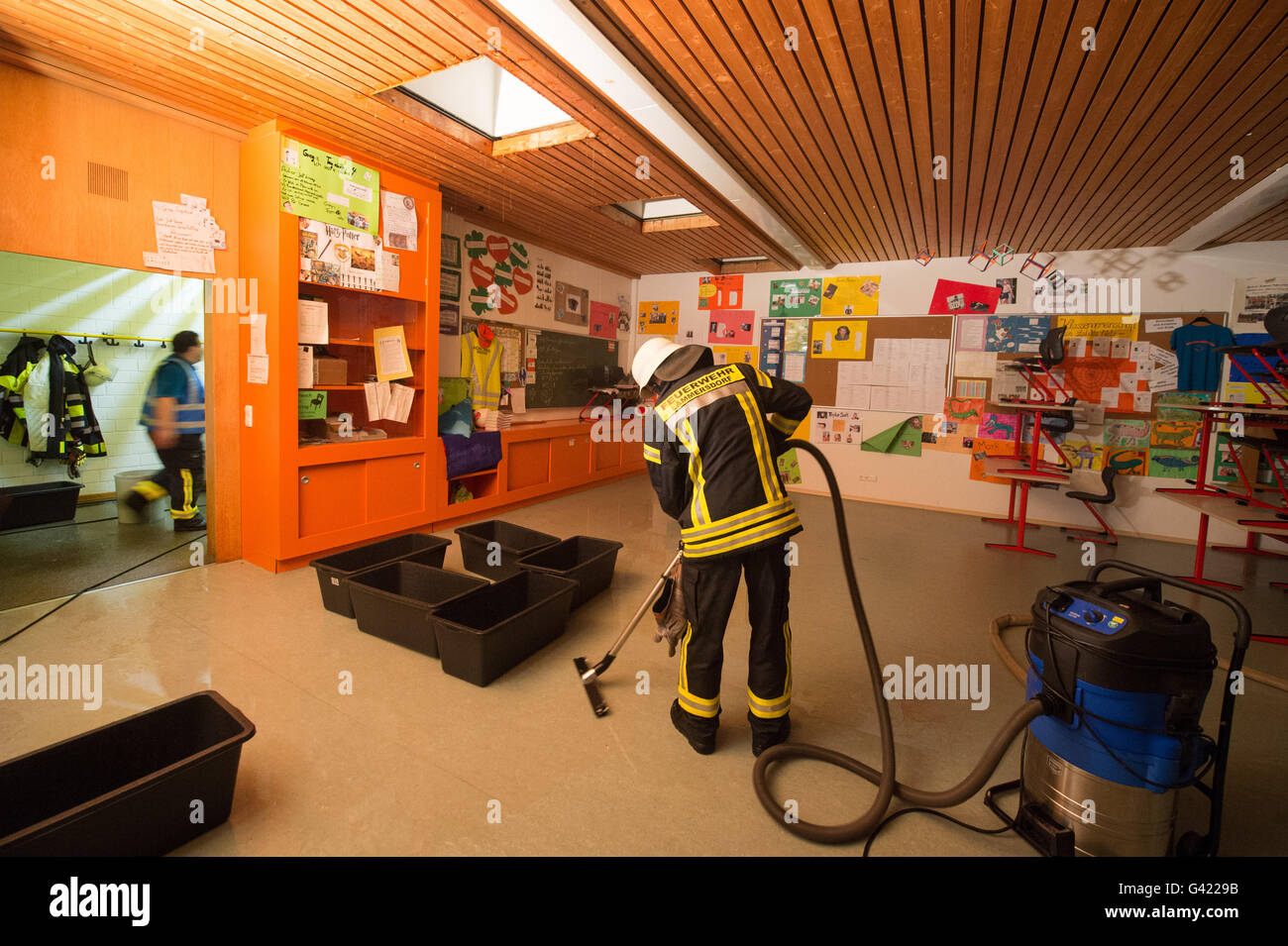 Ruhmannsfelden, Allemagne. 16 Juin, 2016. Un pompier draine une salle de classe à l'école moyenne dans Ruhmannsfelden, Allemagne, 16 juin 2016. Un hailstrom a quitté le toit du bâtiment scolaire si endommagés que l'eau de pluie pourraient pénétrer dans les salles de classe. Photo : Armin Weigel/dpa/Alamy Live News Banque D'Images