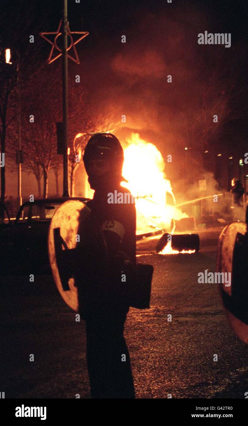 13 DÉCEMBRE: Rupture de roits majeurs à Brixton dans le sud de Londres Un policier en train d'émeute regarde une voiture en feu pendant les perturbations à Brixton, sud de Londres, ce soir (mer). Banque D'Images