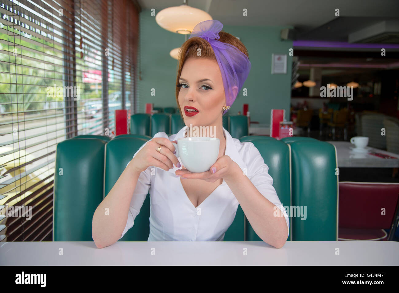 Look années 60 pin up girl dans un restaurant américain avec une tasse de café Banque D'Images