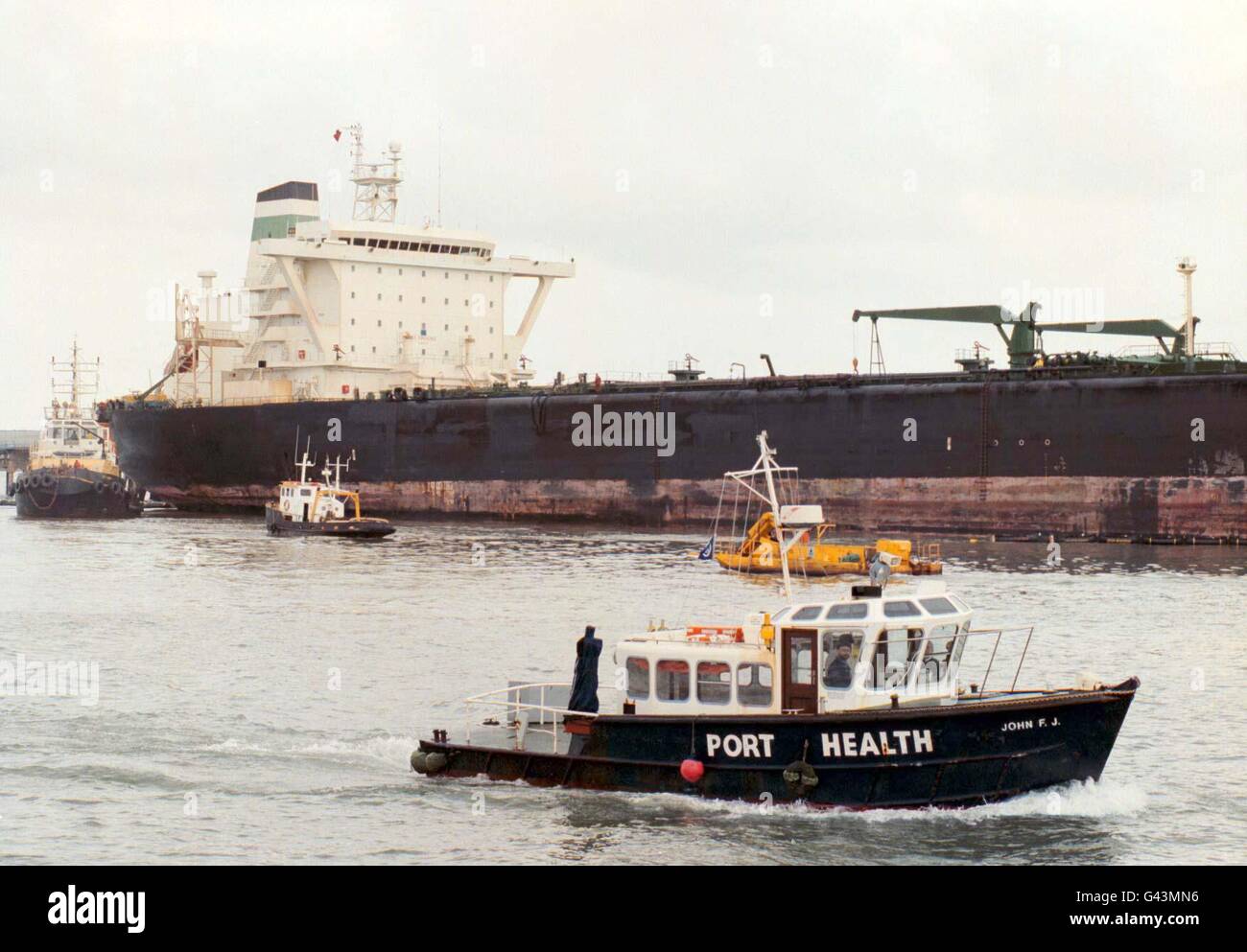 Aujourd'hui (jeudi), le bateau « Port Health » passe devant la berthée « sea Empress » de Milford Haven, alors que les efforts se poursuivaient pour nettoyer la pollution par les hydrocarbures qui s'est emparée de ses chars rompus après qu'elle ait échoué sur les rochers il y a une semaine. Banque D'Images