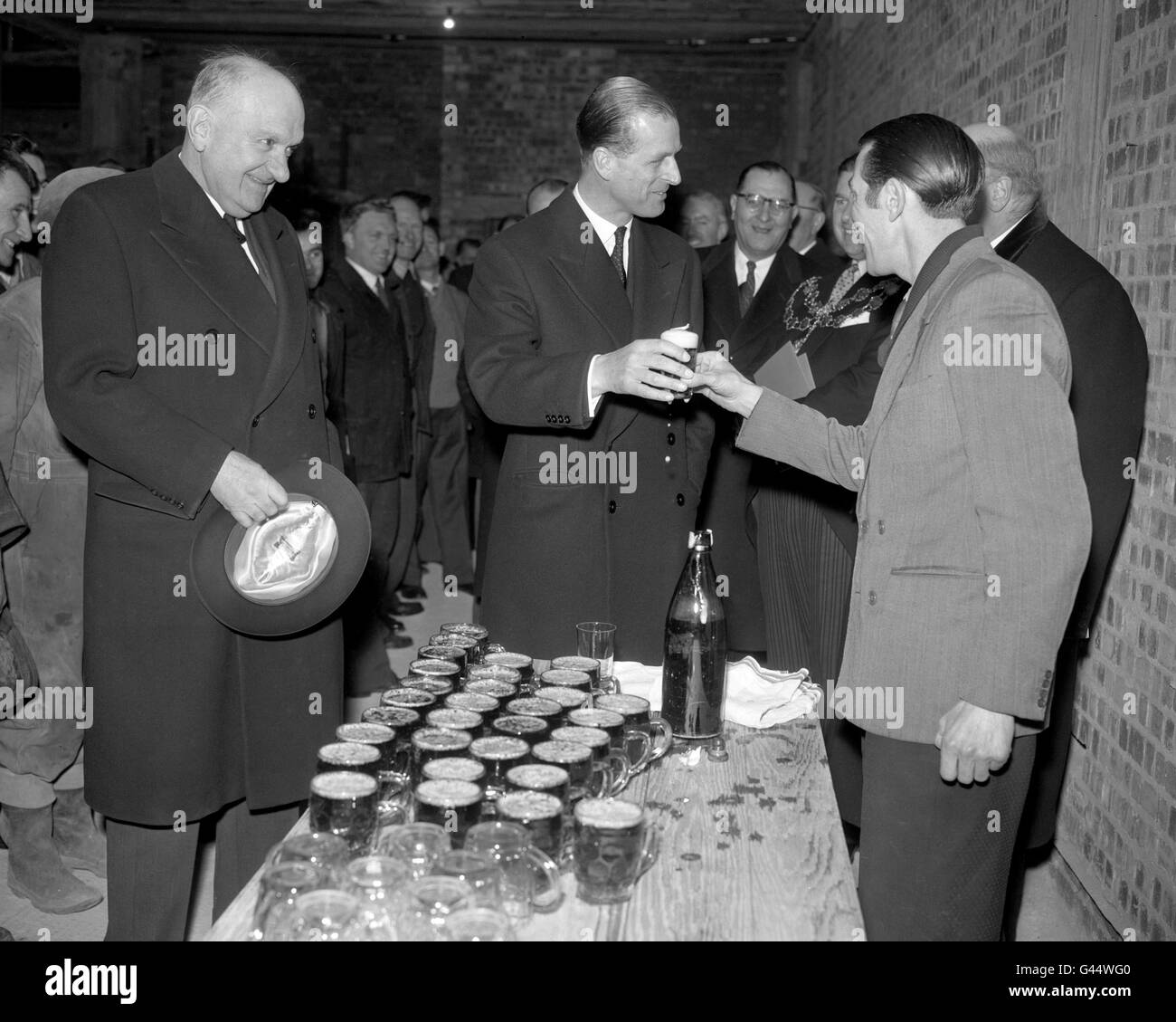 Un verre de bière moussant est accepté par le duc d'Édimbourg par un ouvrier sur le site de la City and Guilds du nouveau siège de l'Institut de Londres à Portland place, Londres, où le duc venait de poser la pierre de fondation. Banque D'Images