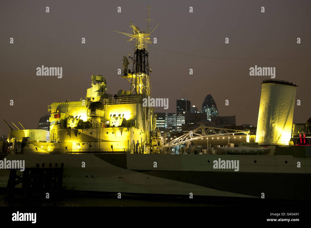 HMS Belfast sur la Tamise à Londres, est illuminé de lumières jaunes, pour marquer le lancement du Grand appel de Daffodil de Marie Curie Caner Care. Banque D'Images