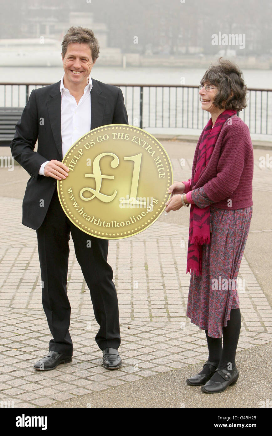 Hugh Grant et co-fondateur de www.healthtalkonline.org Dr Ann McPherson détiennent une pièce géante d'une livre à un photocall sur la South Bank, Londres, pour lancer un appel pour un mille de pièces d'une livre, totalisant 72,000, pour l'organisme de bienfaisance www.healthtalkonline.org,un répertoire vidéo en ligne des enregistrements vidéo et audio des expériences de 63 maladies et problèmes de santé différents. Banque D'Images