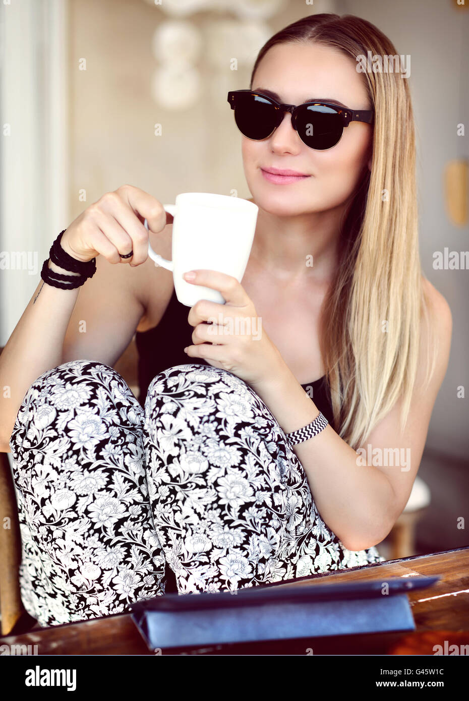 Belle jeune femme de boire du café, élégante jeune fille avec de longs cheveux blonds portant des lunettes à la mode Banque D'Images