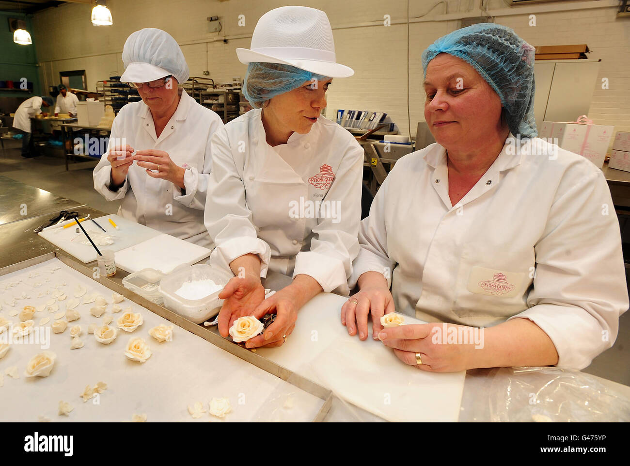 Fiona Cairns (au centre) avec Mary Doody (à droite) et Diane Pallet (à gauche) pour la confection de décorations pour le gâteau de mariage royal, Fleckney, Leicestershire. Mme Cairns a été commandée par le Prince William et Kate Middleton pour créer un gâteau aux fruits traditionnel à plusieurs niveaux, somptueusement décoré d'un thème floral pour leur mariage. Banque D'Images
