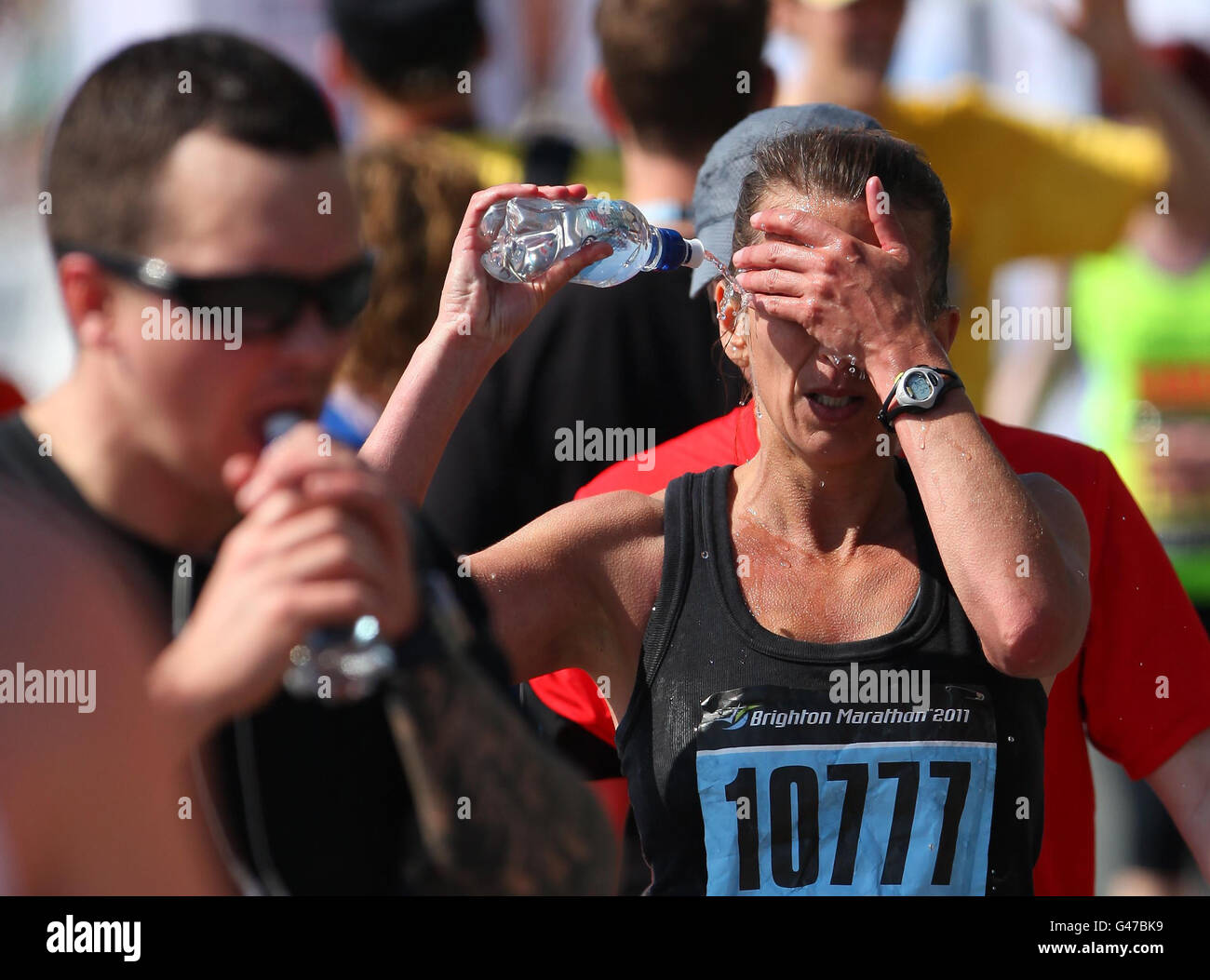 Un concurrent du marathon de Brighton se rafraîchit avec de l'eau après avoir traversé la ligne d'arrivée à Brighton, dans l'est du Sussex, alors que le temps chaud continue. Banque D'Images