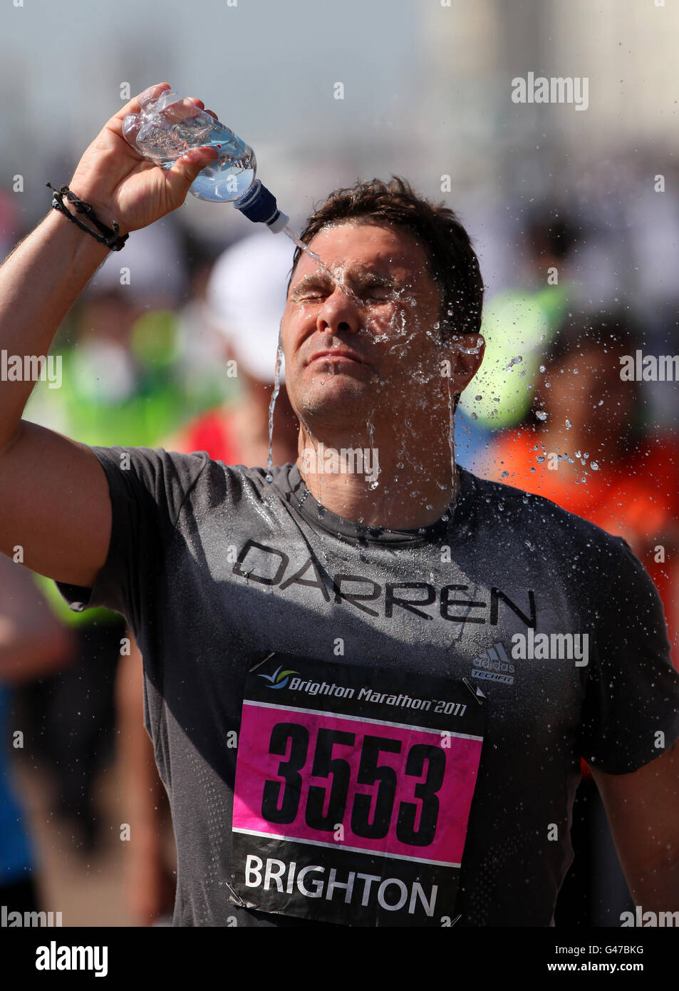 Un concurrent du marathon de Brighton se rafraîchit avec de l'eau après avoir traversé la ligne d'arrivée à Brighton, dans l'est du Sussex, alors que le temps chaud continue. Banque D'Images