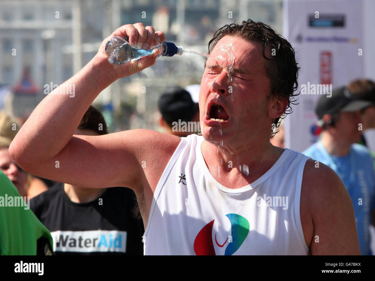 Un concurrent du marathon de Brighton se rafraîchit avec de l'eau après avoir traversé la ligne d'arrivée à Brighton, dans l'est du Sussex, alors que le temps chaud continue. Banque D'Images