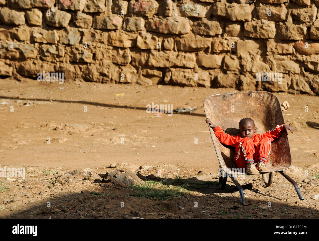 KENYA NAIROBI bidonville Korogocho, garçon assis sans espoir / Kenya Nairobi,genre bidonville Korogocho sitzt hoffnungslos in einer Schubkarre Banque D'Images