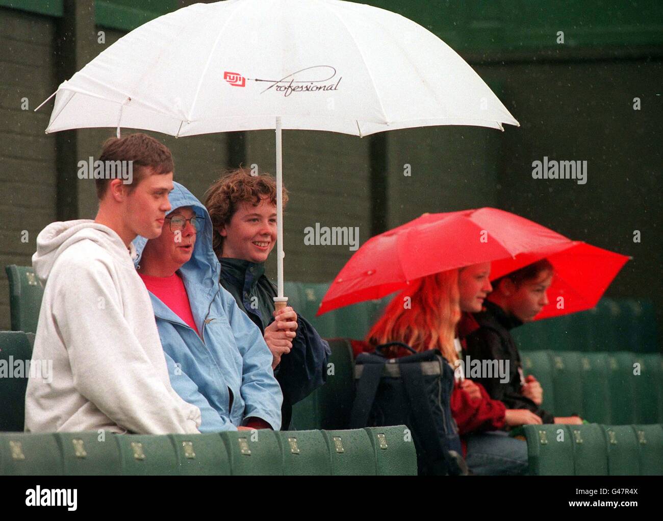 Malgré les conditions météorologiques difficiles, Margo Brarden, 45 ans, fans de Wimbledon, sa fille Kirsty, 19 ans, et John, 18 ans,Qui a voyagé de Glasgow à Londres la semaine dernière pour rester pendant toute la quinzaine, dormant dans une tente, a mis un visage courageux, alors qu'ils se caucus sous leur parapluie (blanc) au sol aujourd'hui (vendredi).Voir PA Story SPORT Wimbledon. Banque D'Images