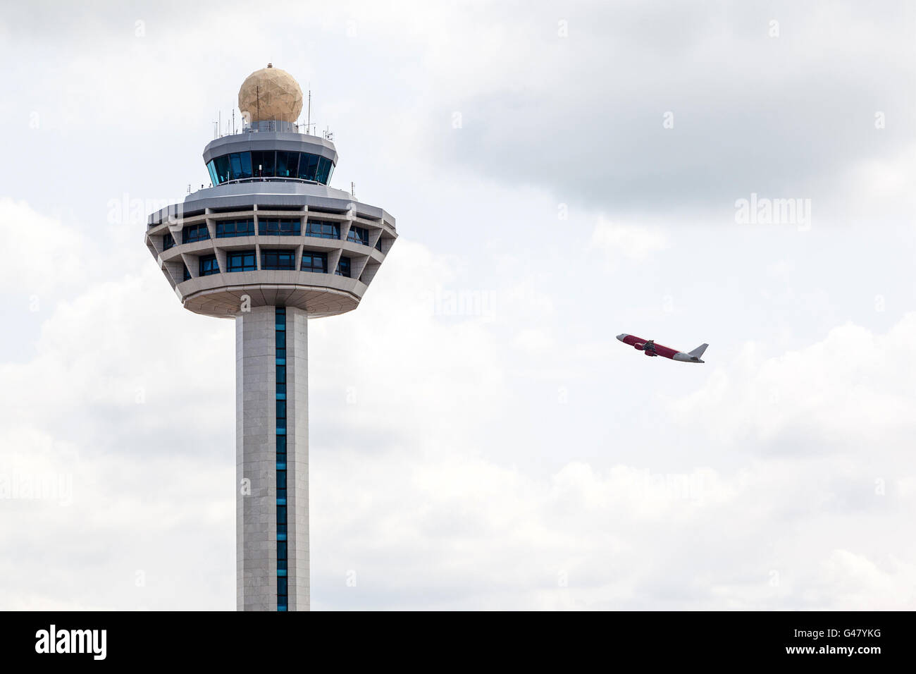 L'aéroport International Changi de Singapour tour contrôleur aérien avec avion décollant dans l'arrière-plan. Banque D'Images