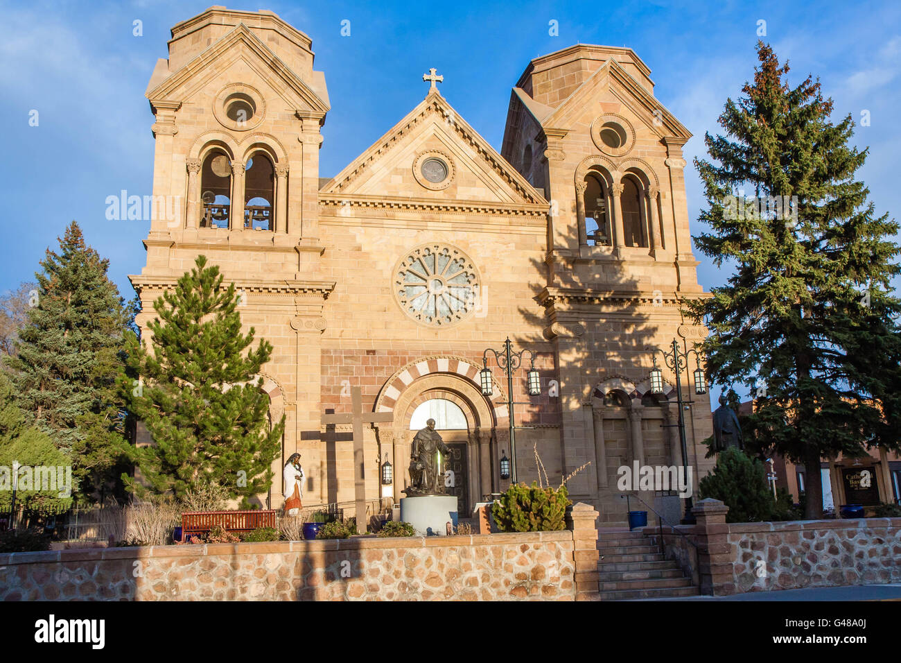 Basilique cathédrale de saint François d'assise au coucher du soleil, Santa Fe, Nouveau Mexique. statue de Saint François en premier plan. Banque D'Images