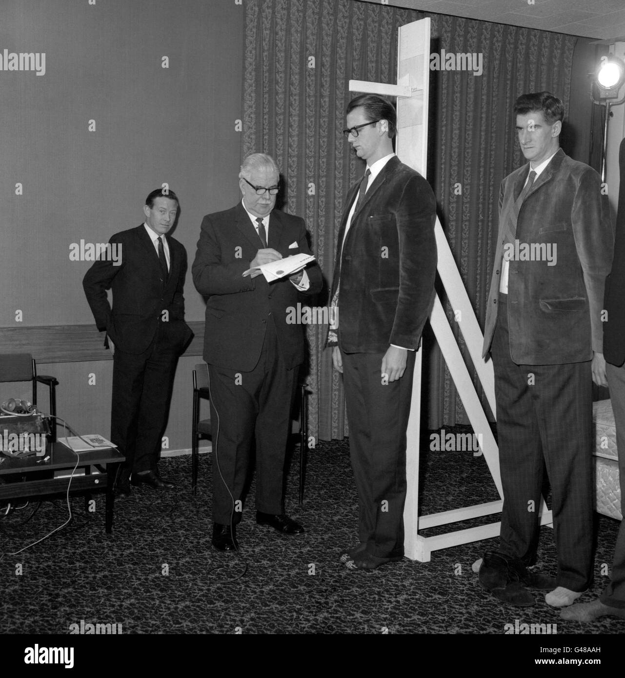 Robin Langford Evans, qui mesure six pieds dix pouces et demi de hauteur, est mesuré par le major Ronald Brittain à l'hôtel Londoner, Londres, lors de la plus haute compétition de l'homme en ville. Banque D'Images