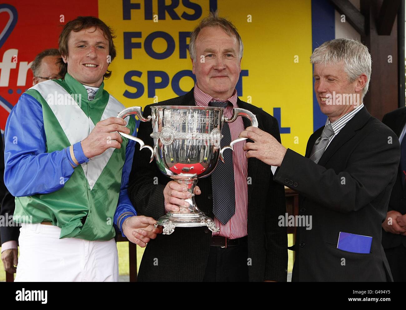 Jockey Jamie Codd (à gauche) célèbre avec le trophée et l'entraîneur J P Dempsey (à droite) après avoir remporté le KFM Hunters Chase Pour la coupelle Bishopscourt sur la presse à balles Banque D'Images