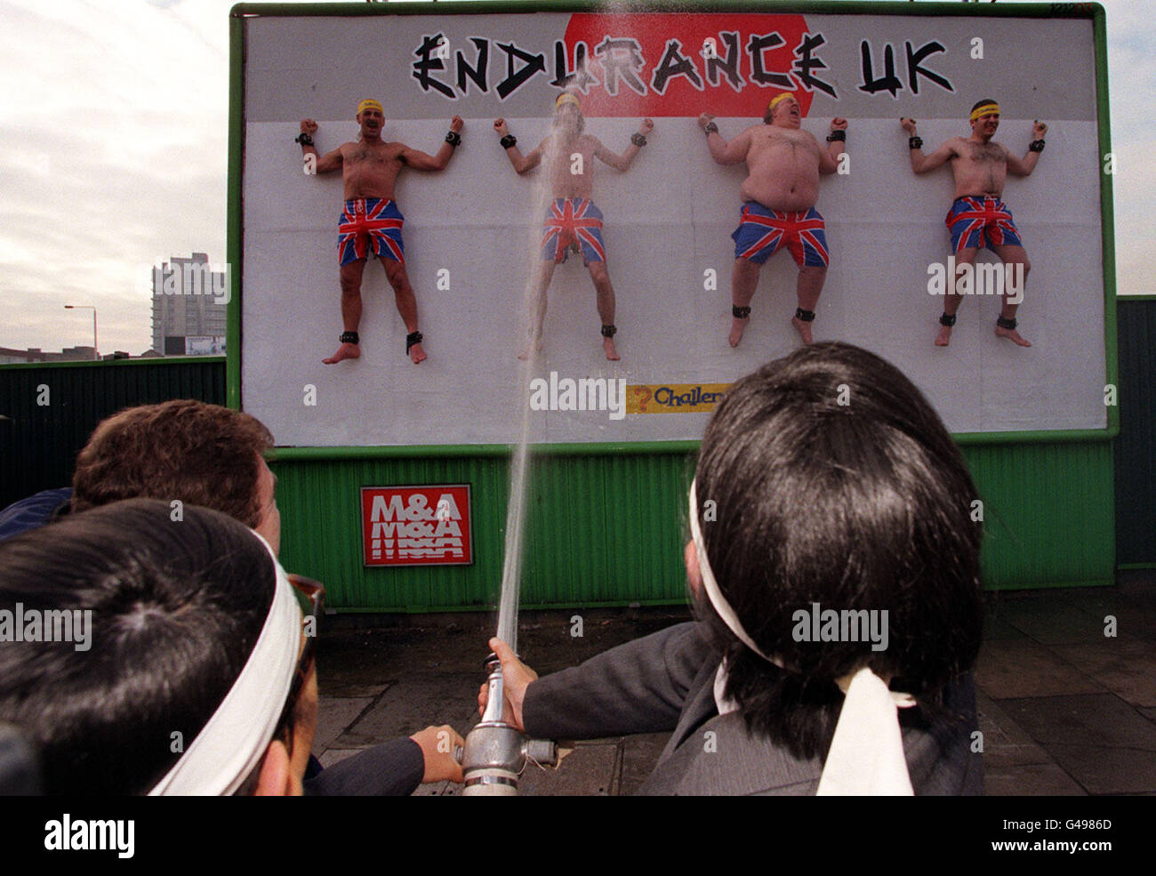 La chaîne câblée et par satellite, Challenge TV, révèle la publicité créative pour la toute nouvelle version britannique du culte japonais jeu show, Endurance UK, avec quatre membres de la chaîne publique enchaînés à un panneau d'affichage à Londres aujourd'hui (vendredi), Paul Ross, l'hôte du spectacle, a fait descendre le fourvers le bas avec l'aide de samurai Sidekicks hoki et Koki. (l/r panneau d'affichage) Glenn Bird, Darren McFerran, Frank Scantori et Brian Timoney. Endurance UK, le test ultime pour le participant ultime, atteint les écrans de télévision britanniques tous les samedis et dimanches soirs à partir du 31 janvier 1998. Photo de Peter Jordan. Banque D'Images