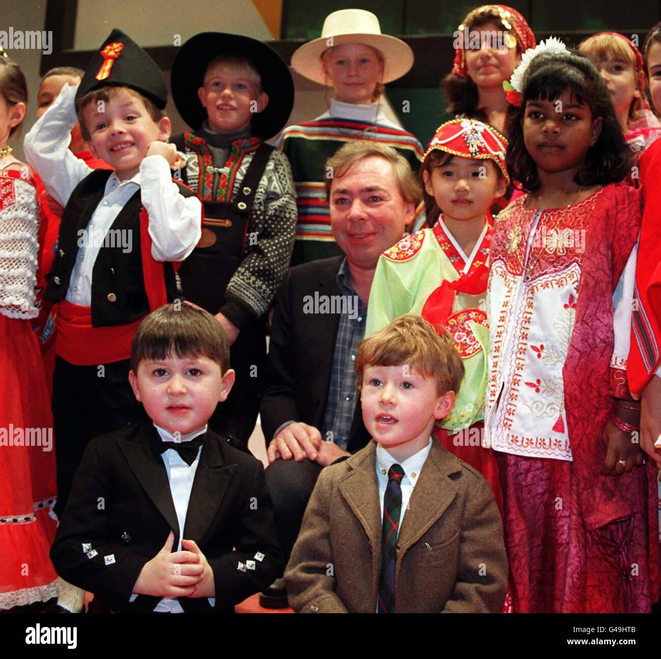 Andrew Lloyd Webber (au centre) est entouré d'enfants vêtus du costume national des pays représentés au World Travel Market à Earls court de Londres aujourd'hui (lundi). Le compositeur a reçu le 'Global Award' de l'industrie du voyage en reconnaissance de sa contribution au tourisme. Les leaders internationaux de l'industrie du voyage disent qu'ils considèrent M. Lloyd Webber, qui a 28 de ses succès dans 13 pays différents, comme l'un des plus influents qui encourage le tourisme aujourd'hui. Photo de Michael Crabtree/PA Banque D'Images