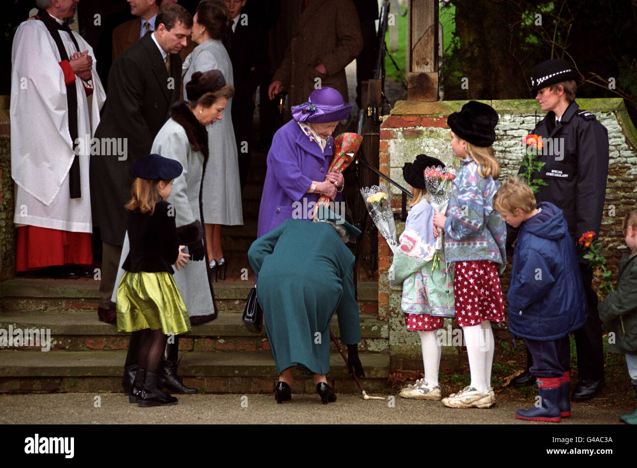 La Reine s'attelle à ramasser le bâton de marche de sa mère, comme le regardent la princesse royale, la princesse Beatrice et le prince Andrew. Autour d'un 1,000 puits de wishers se sont rassemblés à l'extérieur de l'église sur le domaine de Sandringham à Norfolk pour souhaiter aux Royals un joyeux Noël comme ils sont partis après avoir assisté au service du matin. Banque D'Images