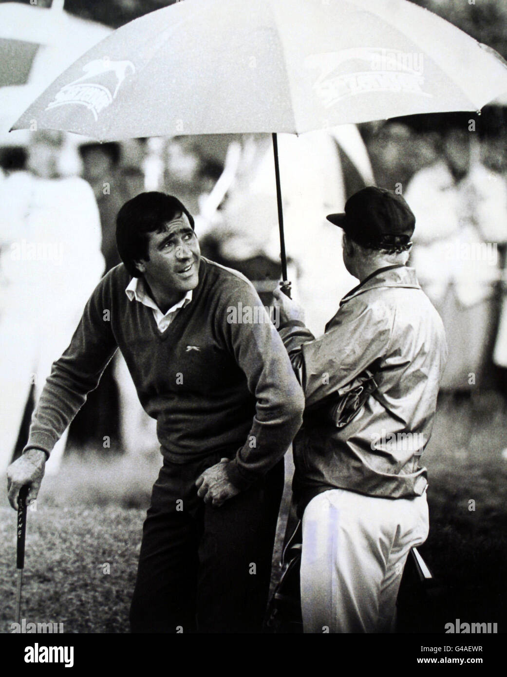 Seve Ballesteros regarde de son parapluie sur le deuxième vert pour voir où se trouve la tempête de tonnerre. Banque D'Images