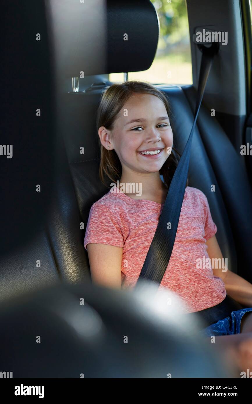 Parution du modèle. Fille dans le siège arrière de la voiture portant la ceinture de sécurité. Banque D'Images