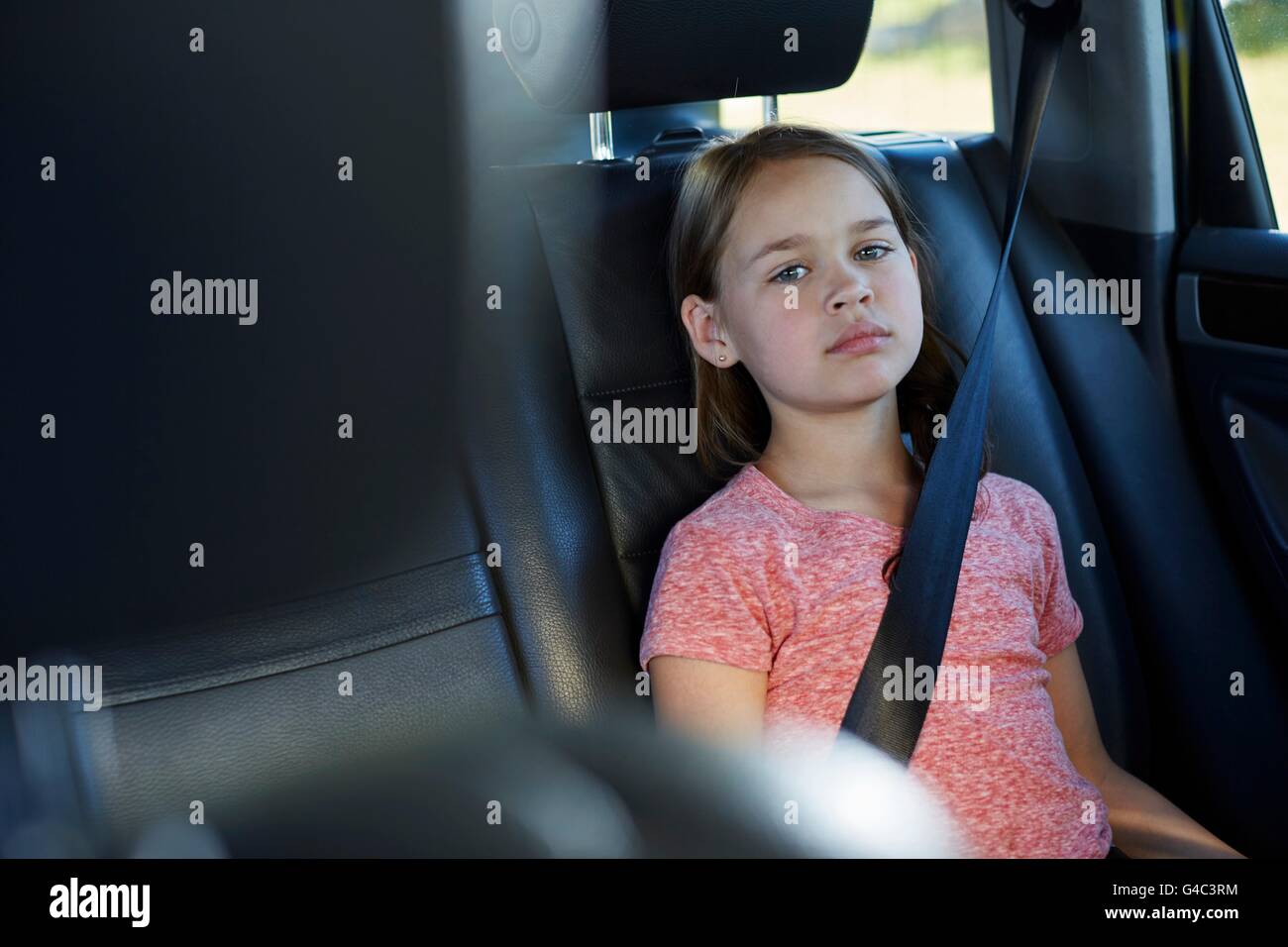 Parution du modèle. Fille dans le siège arrière de la voiture portant la ceinture de sécurité. Banque D'Images