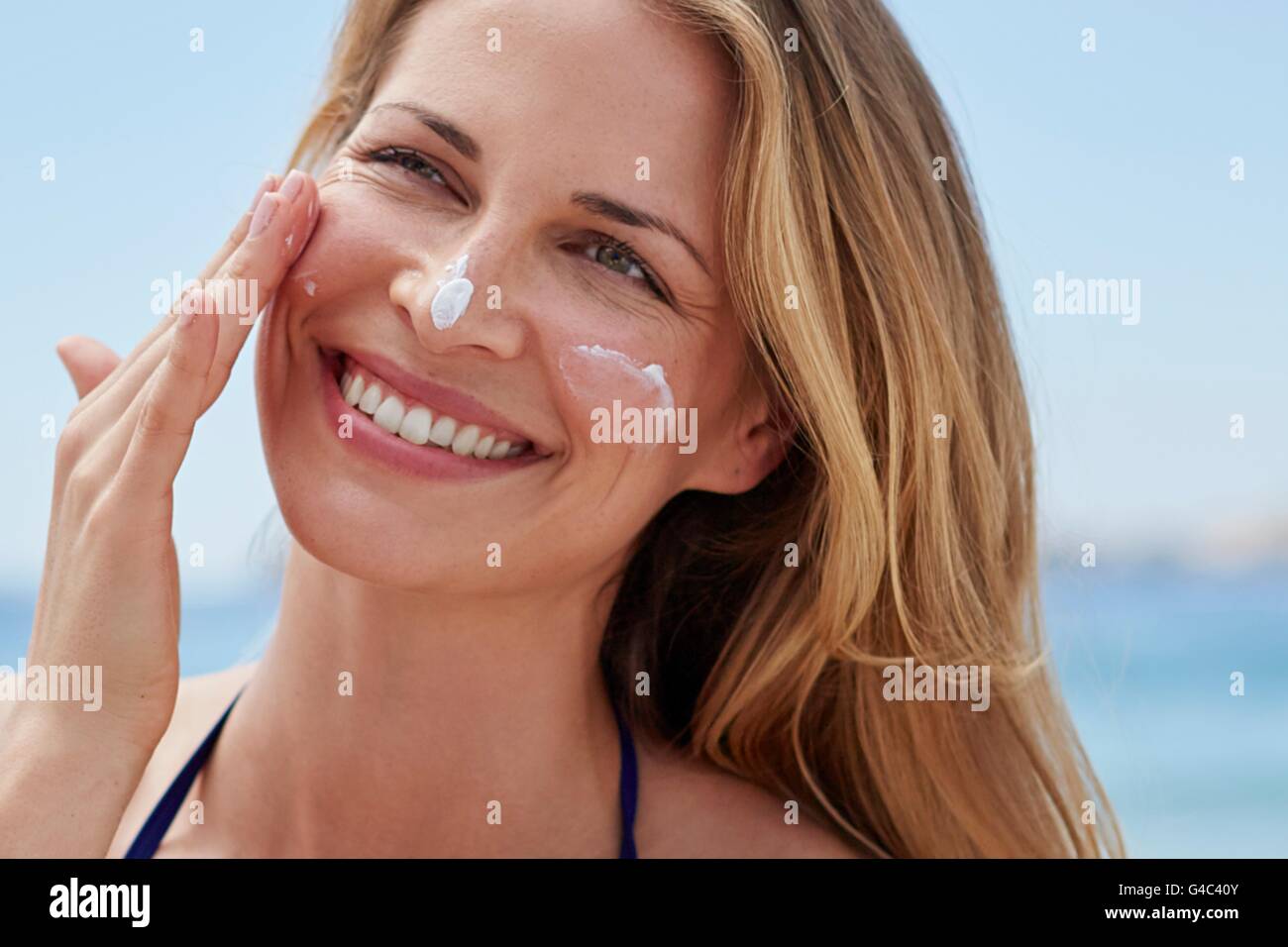 Parution du modèle. Young woman applying sun de la crème. Banque D'Images Parution du modèle. Young woman applying sun de la crème. Banque D'Images