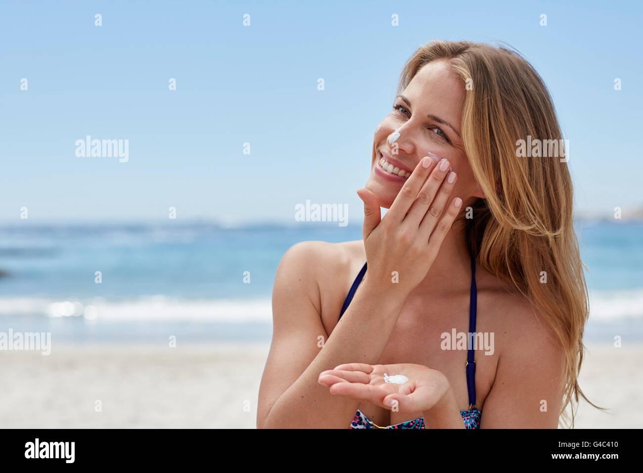 Parution du modèle. Jeune femme l'application de la crème solaire sur la plage. Banque D'Images Parution du modèle. Jeune femme l'application de la crème solaire sur la plage. Banque D'Images