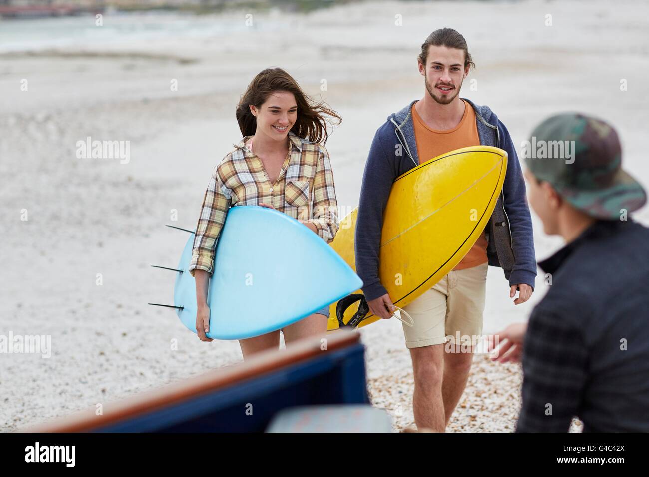 Parution du modèle. Jeune couple on beach with surfboards. Banque D'Images