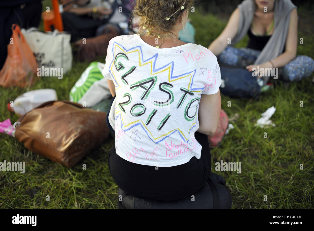 Une fille porte un t-shirt peint à la main tandis que les fêtards se préparent à rentrer du festival Glastonbury, digne Farm, Pilton. Banque D'Images